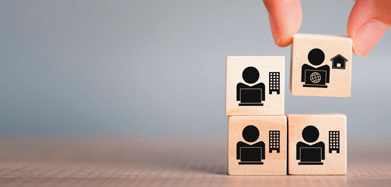 Cubes en bois illustrant le télétravail et le travail transfrontalier, avec icônes maison, bureau et connexion
